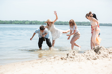 Image showing Seasonal feast at beach resort. Group of friends celebrating, resting, having fun on the beach in sunny summer day