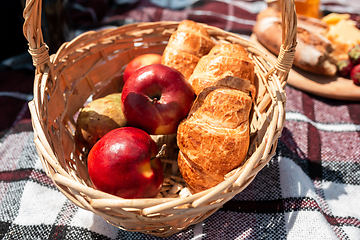 Image showing Picnic bread, croissant basket with fruit on cloth with bright sunlight