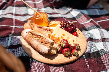 Image showing Picnic bread, croissant basket with fruit on cloth with bright sunlight