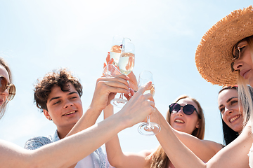 Image showing Seasonal feast at beach resort. Group of friends celebrating, resting, having fun on the beach in sunny summer day