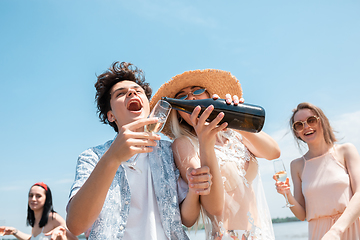 Image showing Seasonal feast at beach resort. Group of friends celebrating, resting, having fun on the beach in sunny summer day