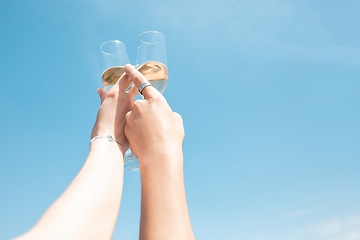 Image showing Seasonal feast at beach resort. Close up hands of friends celebrating, resting, having fun, clinking glasses on sky background