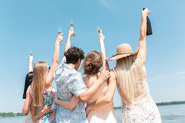 Image showing Seasonal feast at beach resort. Group of friends celebrating, resting, having fun on the beach in sunny summer day