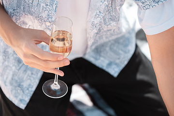 Image showing Seasonal feast at beach resort. Close up hands of man celebrating, resting, having fun, clinking glasses on sky background