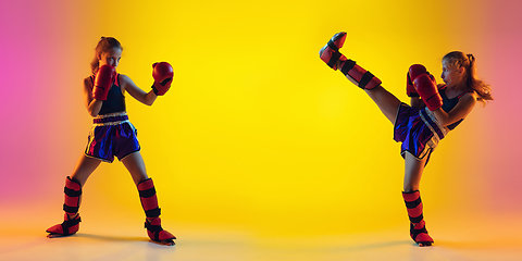 Image showing Little caucasian female kick boxer training on gradient background in neon light, active and expressive