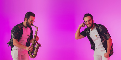 Image showing Young caucasian jazz musician playing the saxophone in neon light, flyer