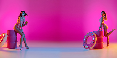 Image showing Fashion portrait of seductive girl in stylish swimwear posing on a bright pink background. Summertime, beach season