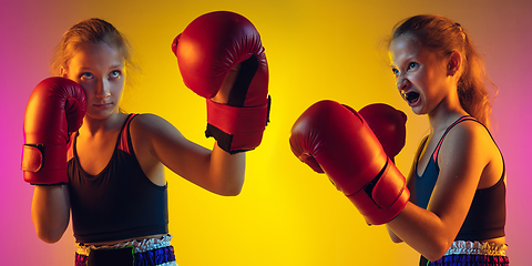 Image showing Little caucasian female kick boxer training on gradient background in neon light, active and expressive