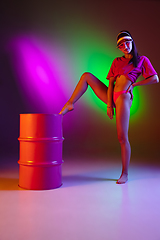 Image showing Beautiful seductive girl in fashionable swimsuit on disco bicolored neon studio background in neon light. Summer, resort, fashion and weekend concept