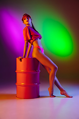 Image showing Beautiful seductive girl in fashionable swimsuit on disco bicolored neon studio background in neon light. Summer, resort, fashion and weekend concept