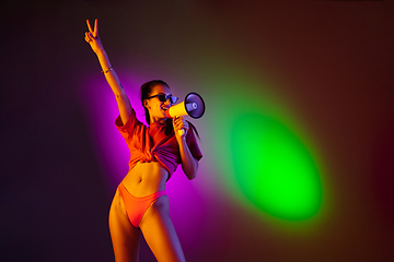 Image showing Beautiful seductive girl in fashionable swimsuit on disco bicolored neon studio background in neon light. Summer, resort, fashion and weekend concept