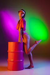 Image showing Beautiful seductive girl in fashionable swimsuit on disco bicolored neon studio background in neon light. Summer, resort, fashion and weekend concept