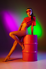 Image showing Beautiful seductive girl in fashionable swimsuit on disco bicolored neon studio background in neon light. Summer, resort, fashion and weekend concept