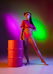 Image showing Beautiful seductive girl in fashionable swimsuit on disco bicolored neon studio background in neon light. Summer, resort, fashion and weekend concept