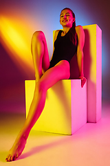 Image showing Beautiful seductive girl in fashionable swimsuit on disco bicolored neon studio background in neon light. Summer, resort, fashion and weekend concept