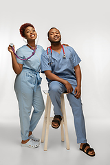 Image showing Couple of beautiful african-american doctors or nurses smiling isolated over white studio background