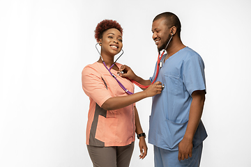 Image showing Couple of beautiful african-american doctors or nurses smiling isolated over white studio background