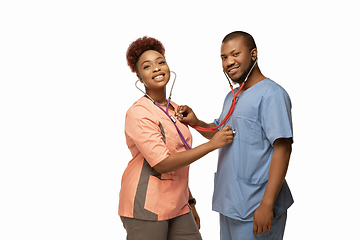 Image showing Couple of beautiful african-american doctors or nurses smiling isolated over white studio background