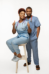 Image showing Couple of beautiful african-american doctors or nurses smiling isolated over white studio background