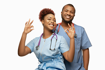 Image showing Couple of beautiful african-american doctors or nurses smiling isolated over white studio background