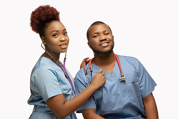 Image showing Couple of beautiful african-american doctors or nurses smiling isolated over white studio background