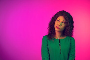 Image showing African-american young woman\'s portrait isolated on gradient pink background in neon light