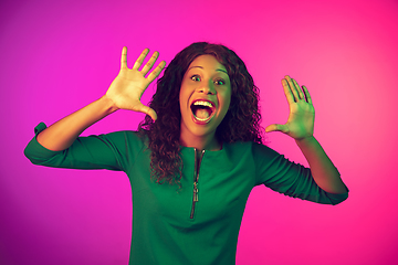 Image showing African-american young woman\'s portrait isolated on gradient pink background in neon light