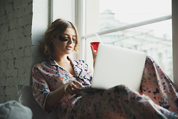 Image showing Portrait of pretty young girl in modern apartment in the morning. Resting, calm, salisfied. Youth and wellness concept.