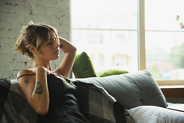 Image showing Portrait of pretty young girl in modern apartment in the morning. Resting, calm, salisfied. Youth and wellness concept.