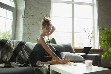 Image showing Portrait of pretty young girl in modern apartment in the morning. Resting, calm, salisfied. Youth and wellness concept.