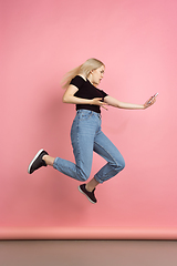 Image showing Portrait of young caucasian woman with bright emotions on coral pink studio background