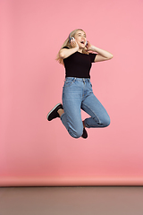 Image showing Portrait of young caucasian woman with bright emotions on coral pink studio background