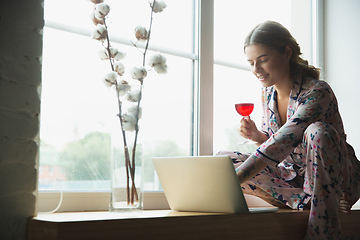 Image showing Portrait of pretty young girl in modern apartment in the morning. Resting, calm, salisfied. Youth and wellness concept.