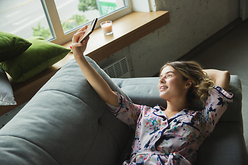 Image showing Portrait of pretty young girl in modern apartment in the morning. Resting, calm, salisfied. Youth and wellness concept.