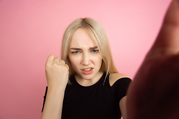 Image showing Portrait of young caucasian woman with bright emotions on coral pink studio background