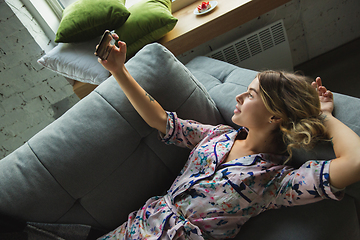 Image showing Portrait of pretty young girl in modern apartment in the morning. Resting, calm, salisfied. Youth and wellness concept.