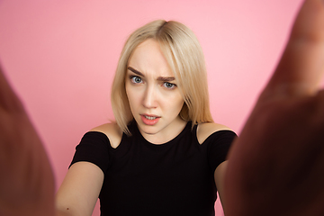 Image showing Portrait of young caucasian woman with bright emotions on coral pink studio background