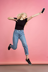 Image showing Portrait of young caucasian woman with bright emotions on coral pink studio background