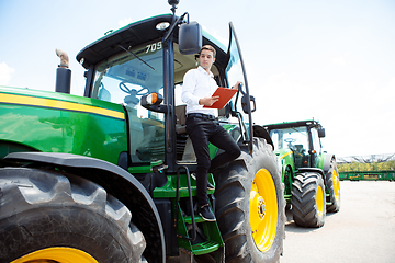 Image showing A farmer with a tractor, combine at a field in sunlight. Confident, bright colors