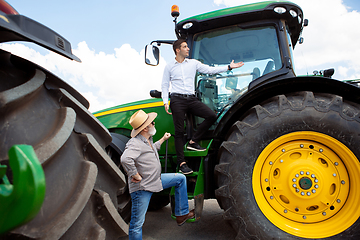 Image showing A farmer with a tractor, combine at a field in sunlight. Confident, bright colors