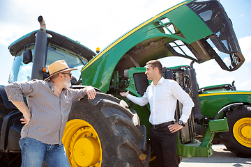 Image showing A farmer with a tractor, combine at a field in sunlight. Confident, bright colors