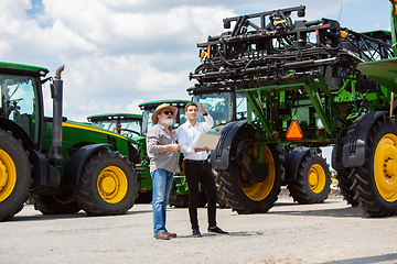 Image showing A farmer with a tractor, combine at a field in sunlight. Confident, bright colors