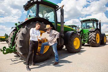 Image showing A farmer with a tractor, combine at a field in sunlight. Confident, bright colors