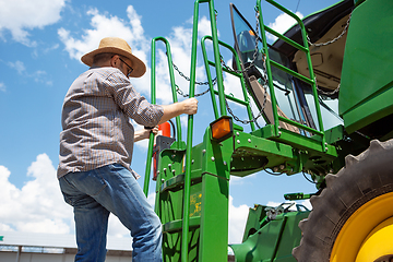 Image showing A farmer with a tractor, combine at a field in sunlight. Confident, bright colors