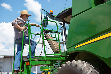 Image showing A farmer with a tractor, combine at a field in sunlight. Confident, bright colors