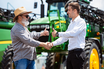 Image showing A farmer with a tractor, combine at a field in sunlight. Confident, bright colors