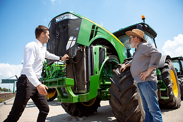 Image showing A farmer with a tractor, combine at a field in sunlight. Confident, bright colors