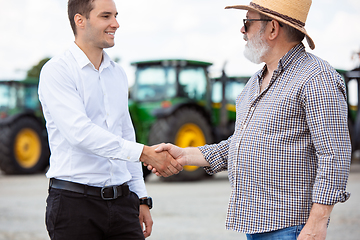 Image showing A farmer with a tractor, combine at a field in sunlight. Confident, bright colors