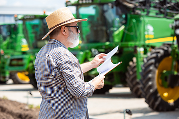 Image showing A farmer with a tractor, combine at a field in sunlight. Confident, bright colors