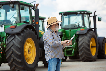 Image showing A farmer with a tractor, combine at a field in sunlight. Confident, bright colors